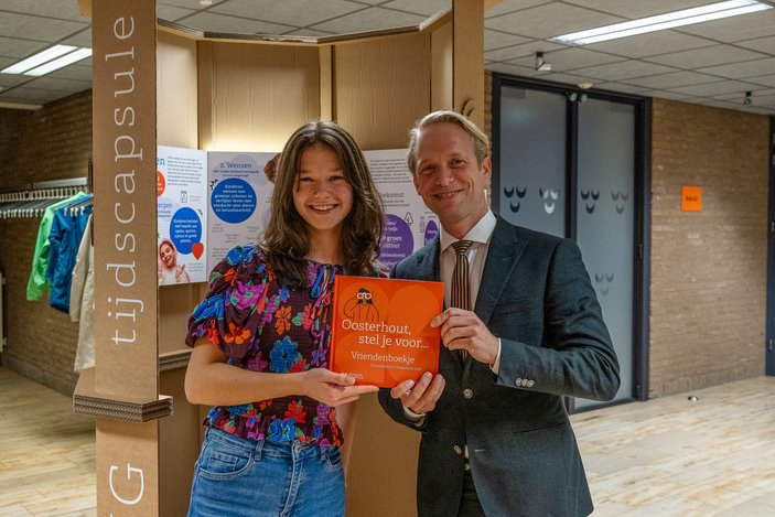 Burgemeester van Grootheest overhandigt het eerste vriendenboekje ‘Vrienden van Oosterhout’ aan Fien. Foto: Casper van Aggelen. 