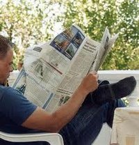 man leest bekendmakingen in een krant